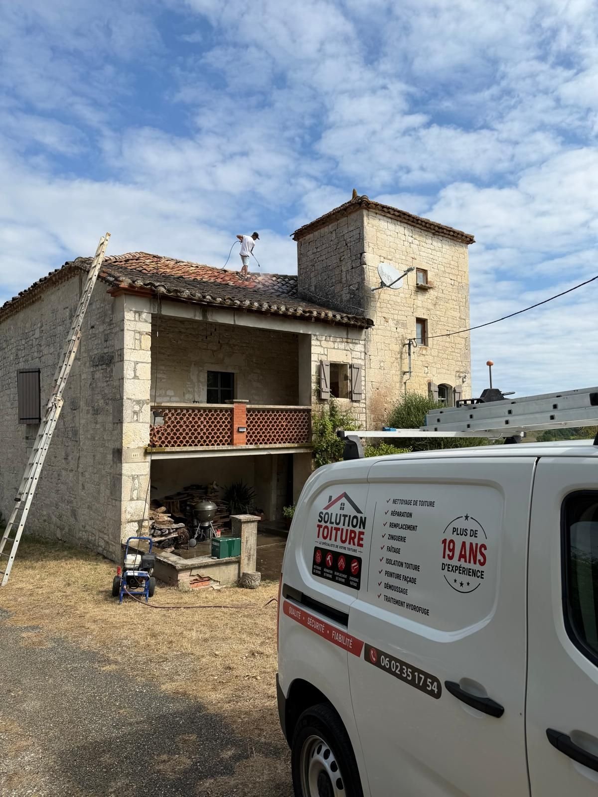 Le fourgon de Solution Toiture, floqué au nom de l'entreprise, stationné devant une bâtisse de pierre en cours de chantier.