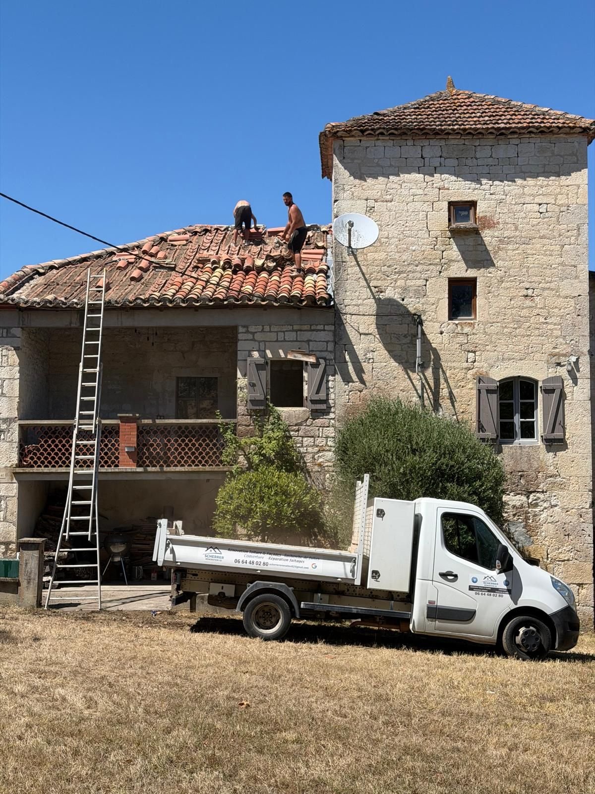 Chantier en cours : camion benne et échelle au pied du bâtiment, un couvreur sur le versant.