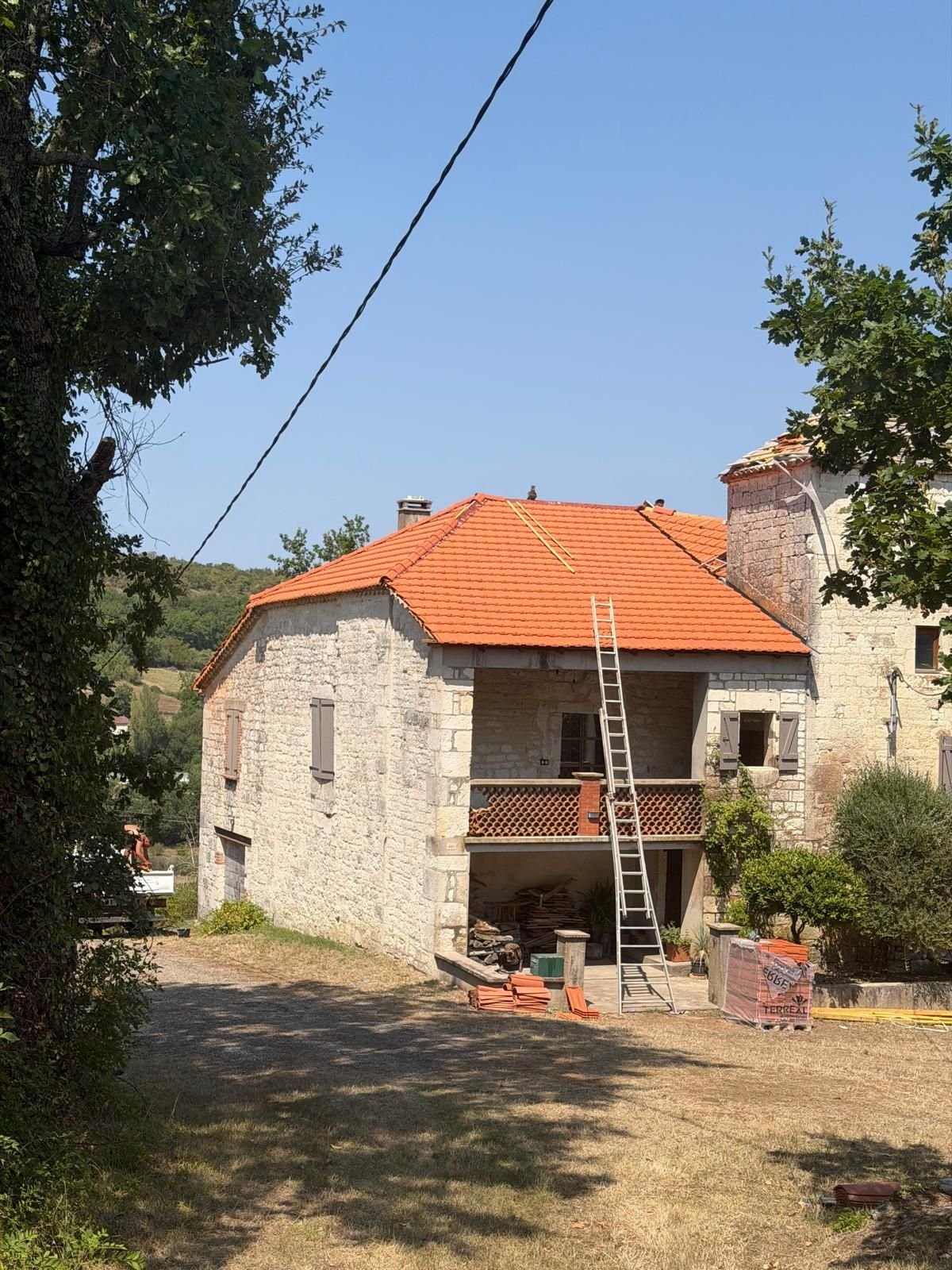 Le bâtiment après travaux : couverture neuve en tuile rouge, allée dégagée et abords nettoyés.