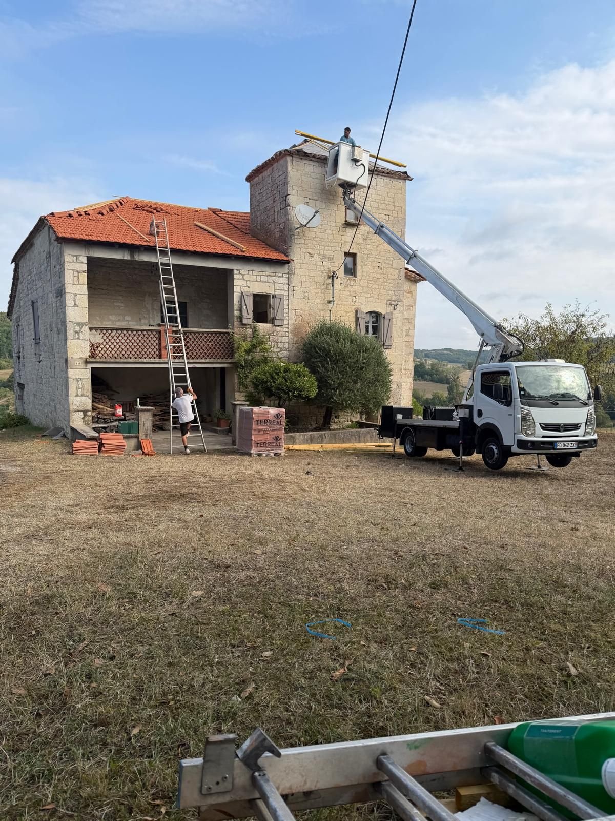 Nacelle élévatrice déployée au pied de la tour pour atteindre la toiture haute.