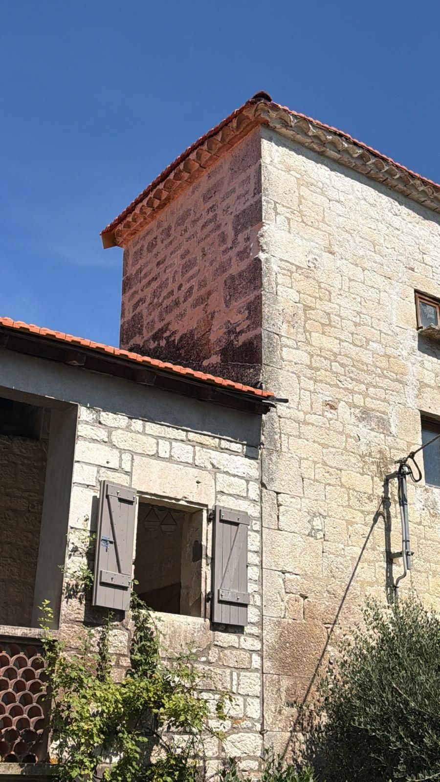 La tour et sa toiture à quatre pans refaite en tuile, au-dessus du corps de bâtiment en pierre.